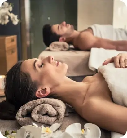 Two people receiving a relaxing couples massage side by side in a spa setting.